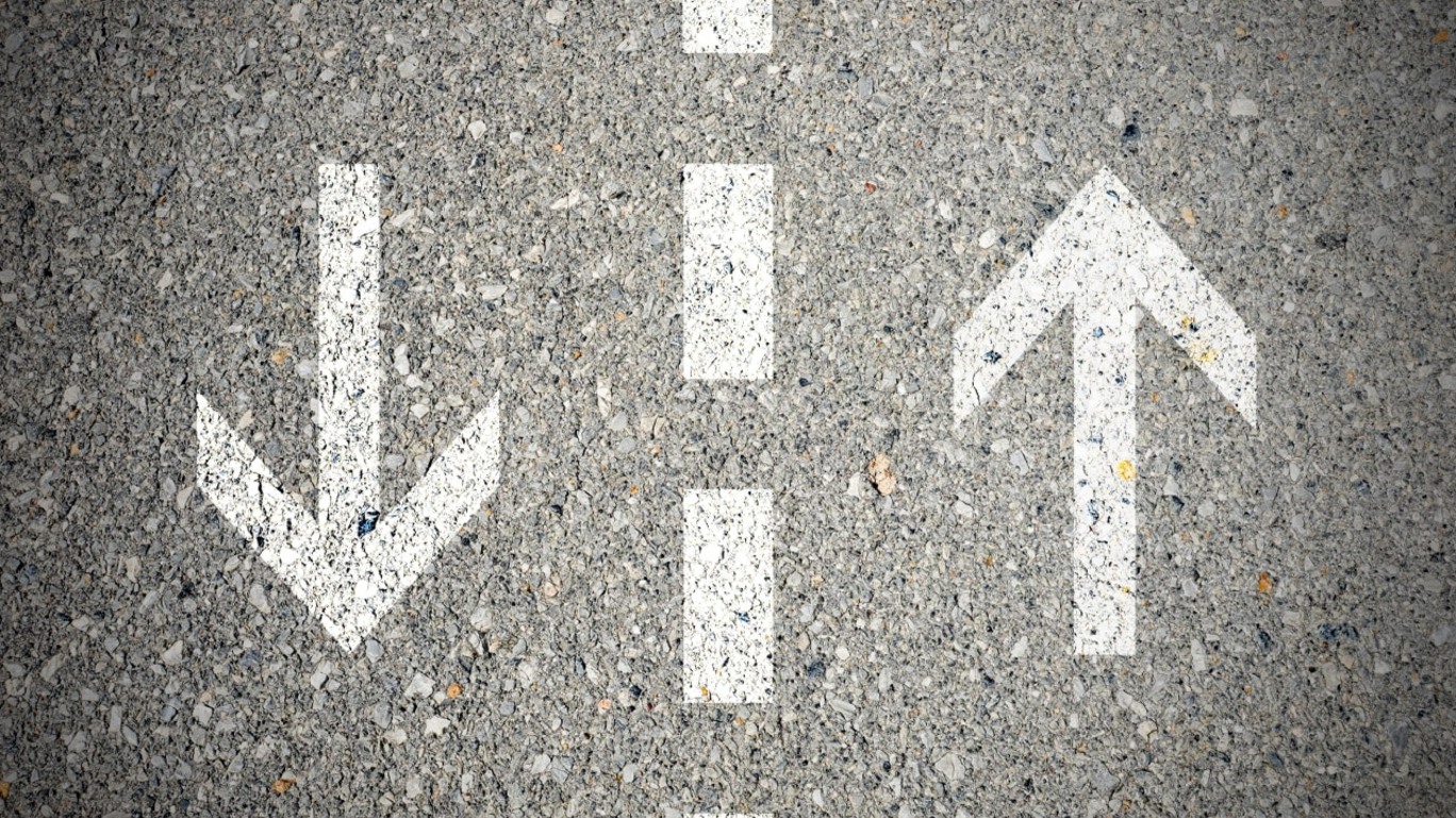 Imagem em close de marcações no asfalto numa via de duas mãos, com uma seta para cima e outra para baixo.