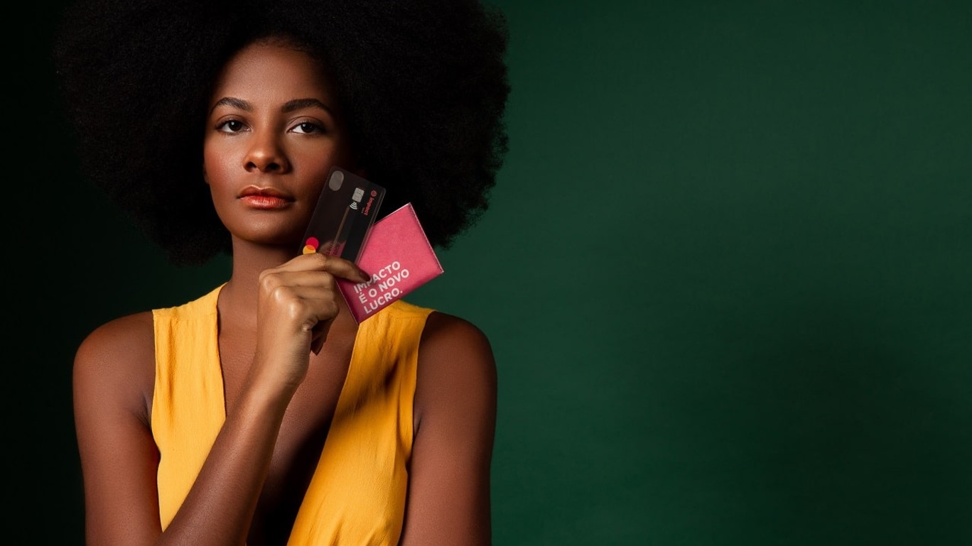 Modelo exibe cartão do Impact Bank em imagem de campanha publicitária