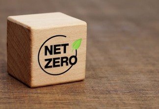 Bloco de madeira com a inscrição "net zero" em cima de mesa de madeira.
