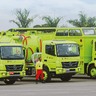 três caminhões verdes enfileirados cada um com um operador à frente