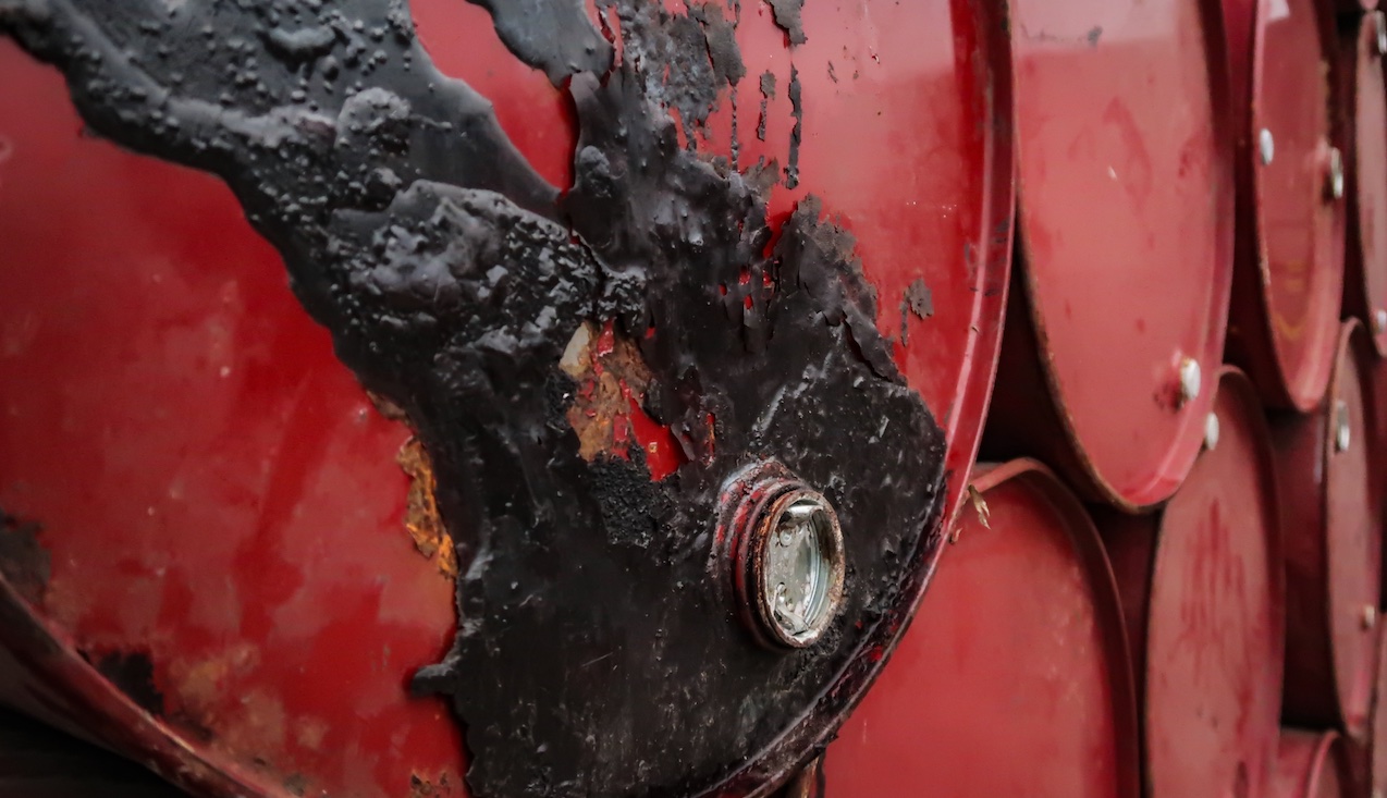 Pilha de barris de petróleo com um deles manchado em primeiro plano Pilha de barris de petróleo com um deles manchado em primeiro plano